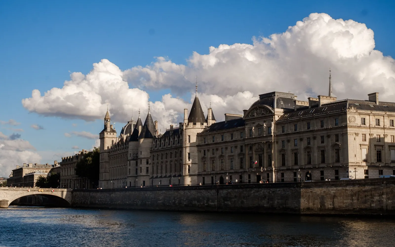 The Conciergerie and the Palais de Justice stretched along the Seine below a sky of summer clouds